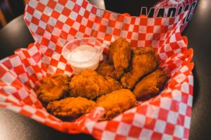 Crispy buffalo chicken wings in a basket with dipping sauce