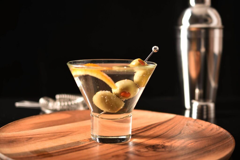 Dirty martini cocktail garnished with green olives on a wooden bar