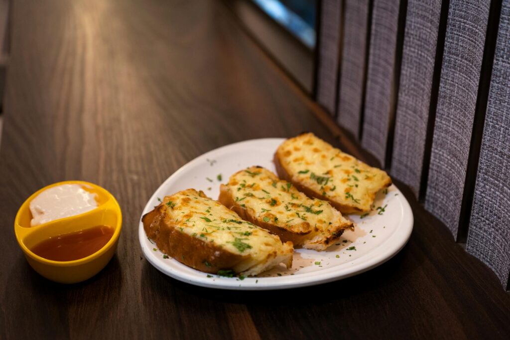 Cheesy garlic bread served golden and crispy on a plate with dip