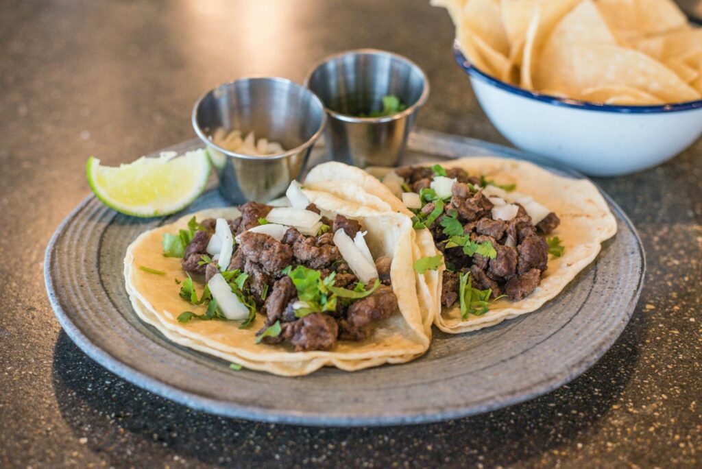 Beef tacos with seasoned beef, cilantro, onion, and lime served on a rustic plate