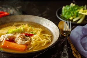 Classic chicken noodle soup with egg noodles, shredded chicken, and carrots in a rustic bowl
