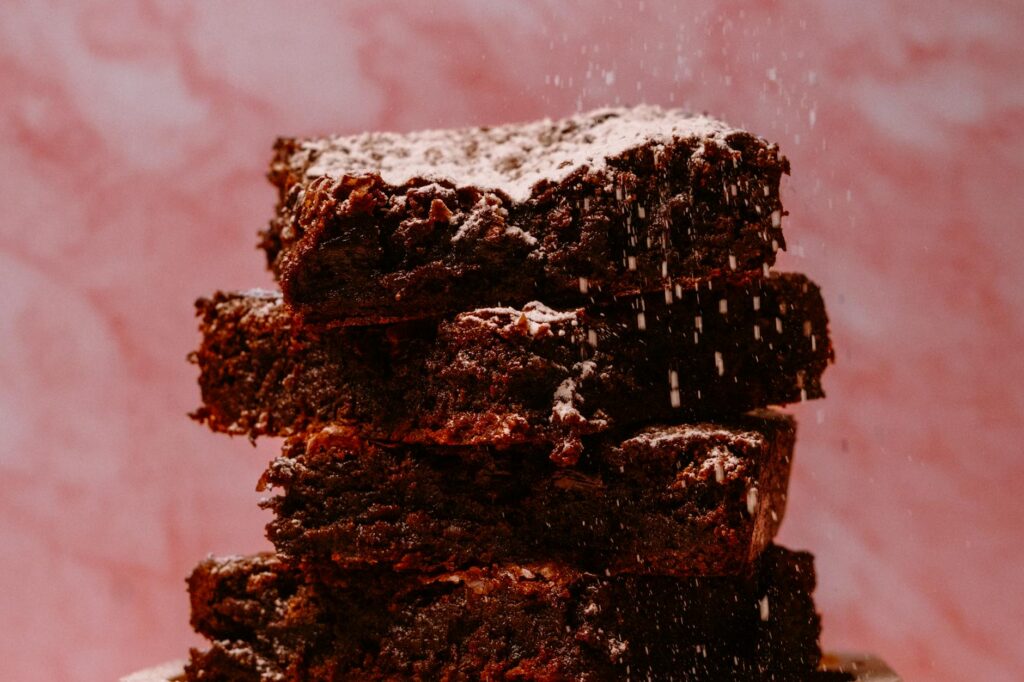 Stack of fudgy chocolate brownies dusted with powdered sugar, rich and gooey
