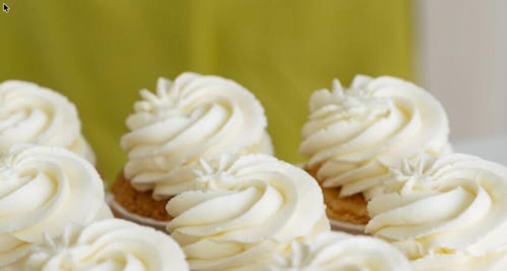 Vanilla cupcakes topped with swirls of silky white vanilla buttercream frosting